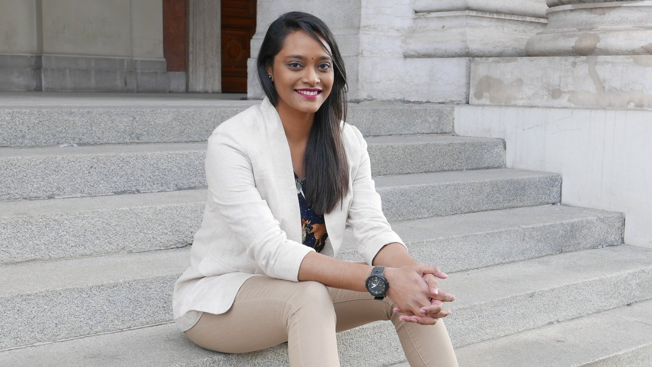 Sumita Kunashakaran sitting on the stars of the House of Philanthropy, smiling and wearing a beige blazer.