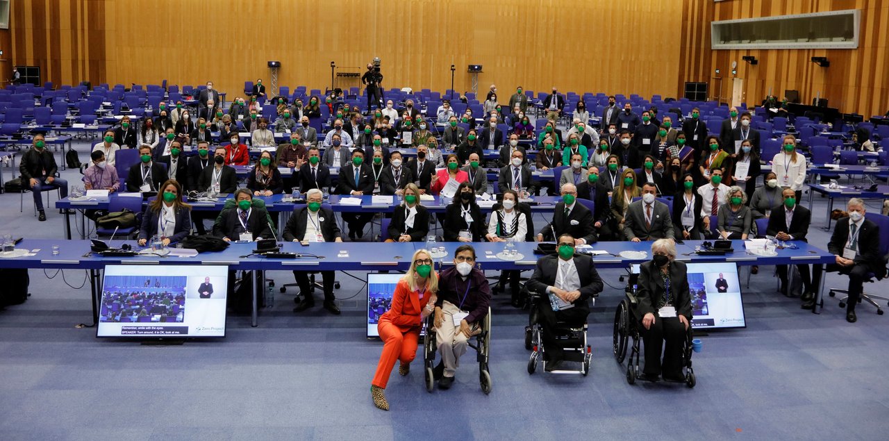 ZeroCon22 group picture of attendees at the UN: a large group of people all wearing masks and with some physical distancing between them. In the plenary room at the UN