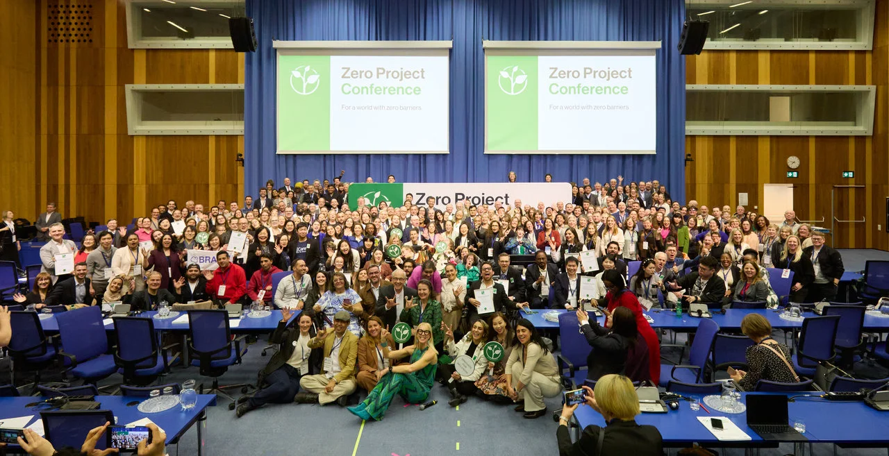 The iconic "family photo" - hundreds of attendees of the Award Ceremony at the Zero Project Conference are pictured posing for the camera, smiling and cheering.