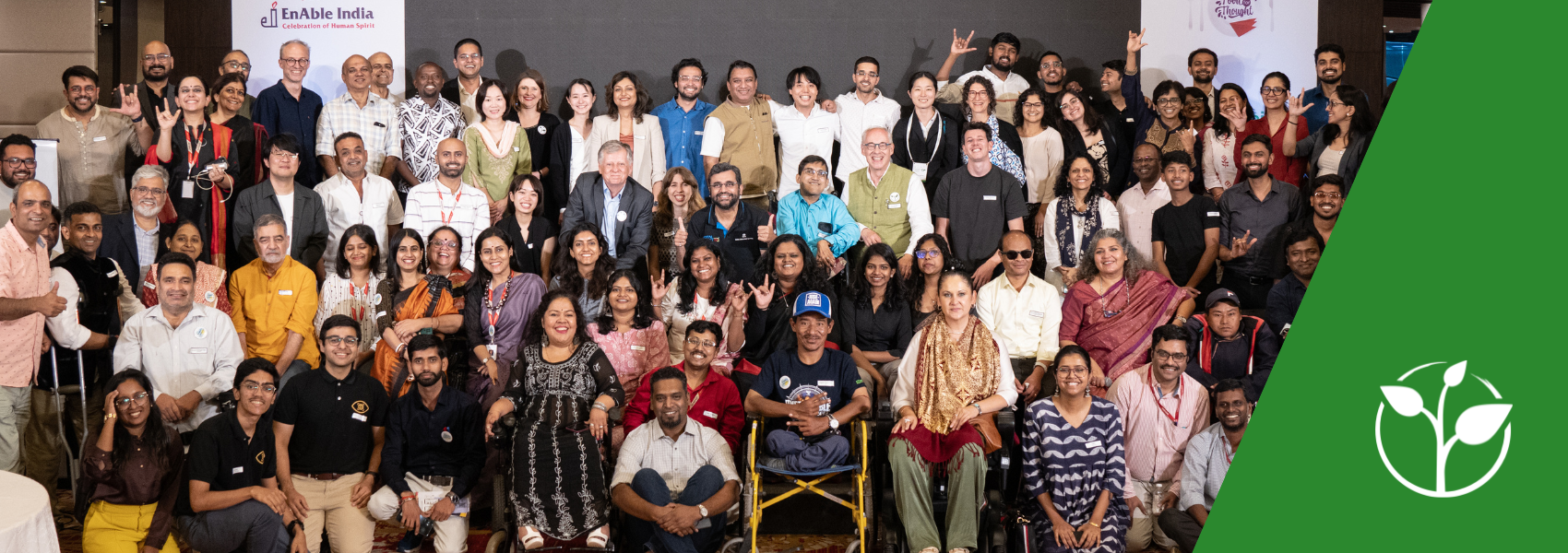 The banner shows a group photo of all "Food for Thought 2024" participants - a very divers group of around 100 people smile into the camera. The Enable India logo can be seen in the background.